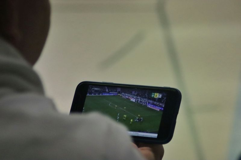 A man is playing a soccer game on his phone